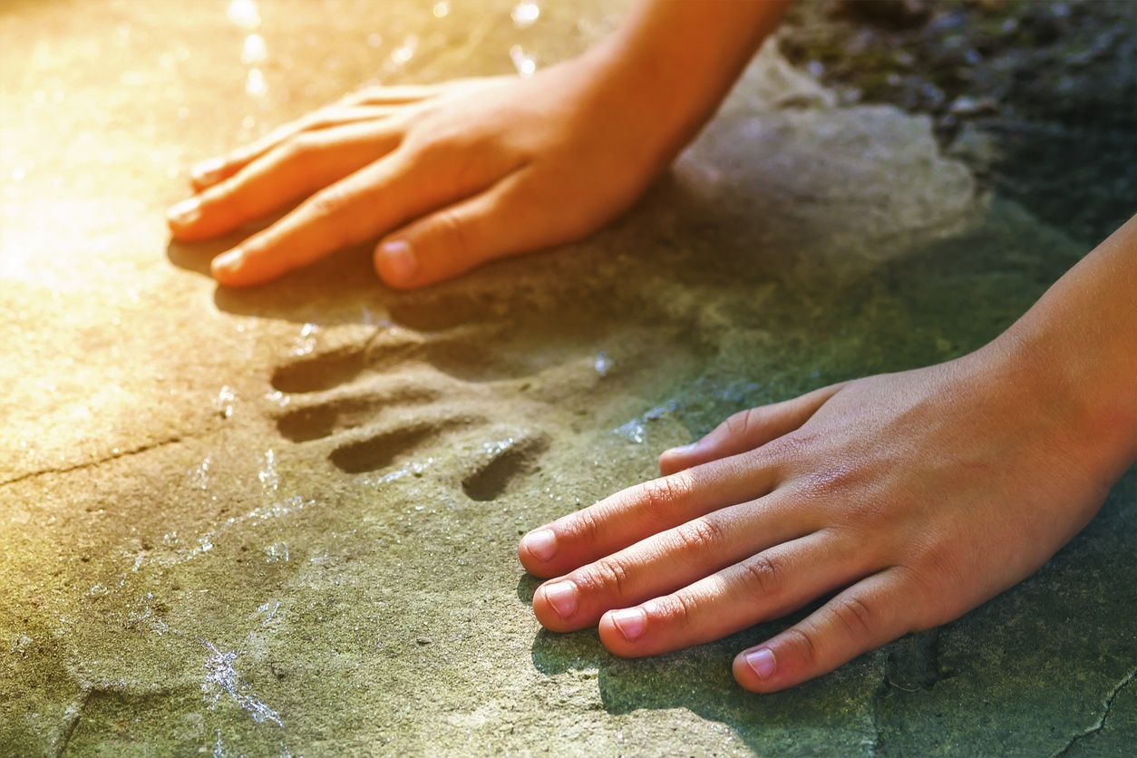 Child's hand next to a smaller handprint in concrete.