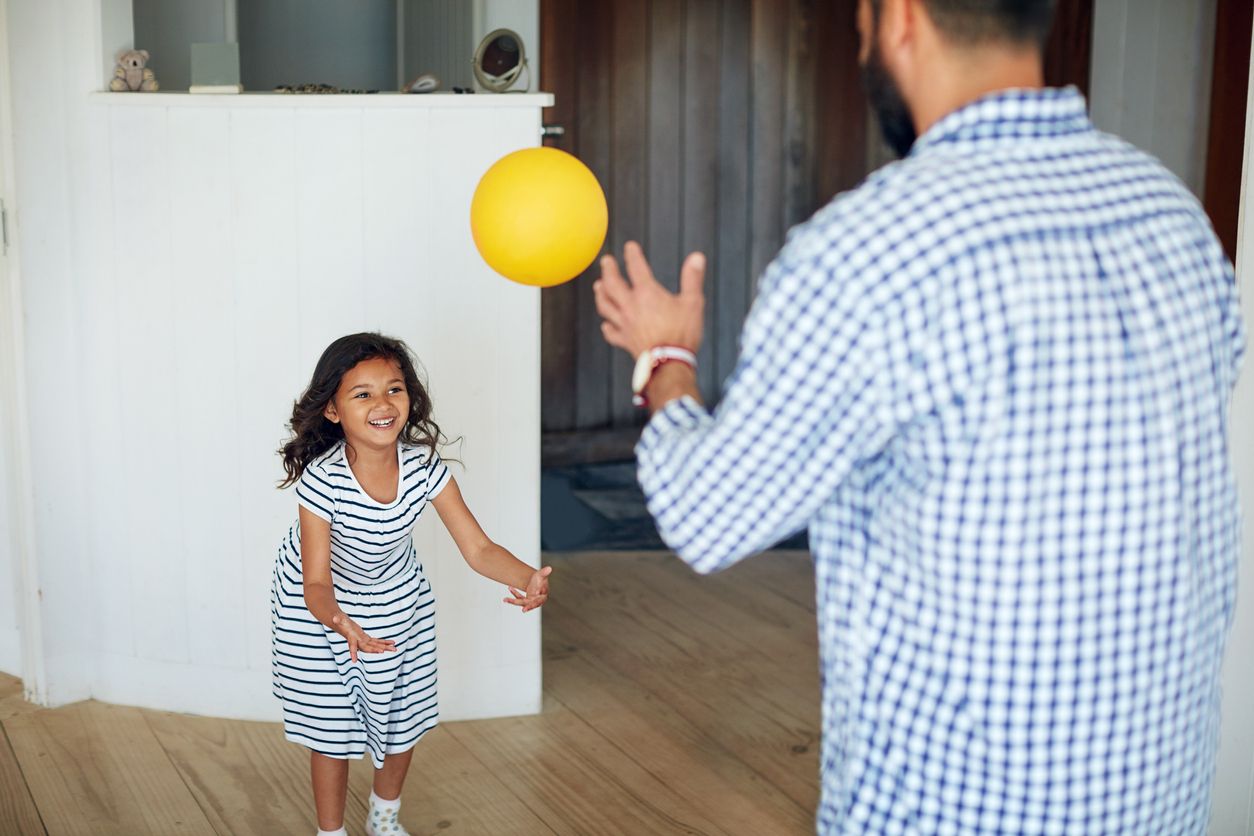 Father teaching daughter how to catch a ball.