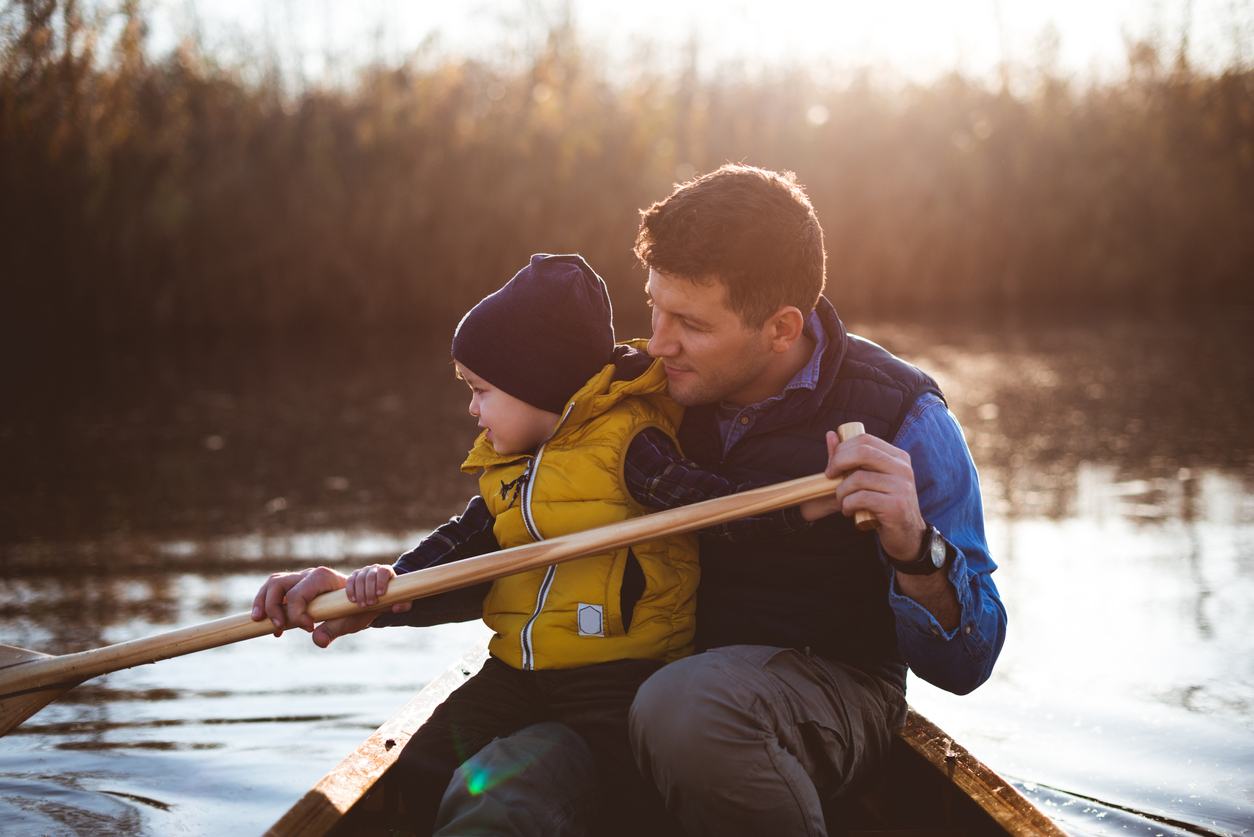 Father and son in a rowboat, father teaching son how to row.