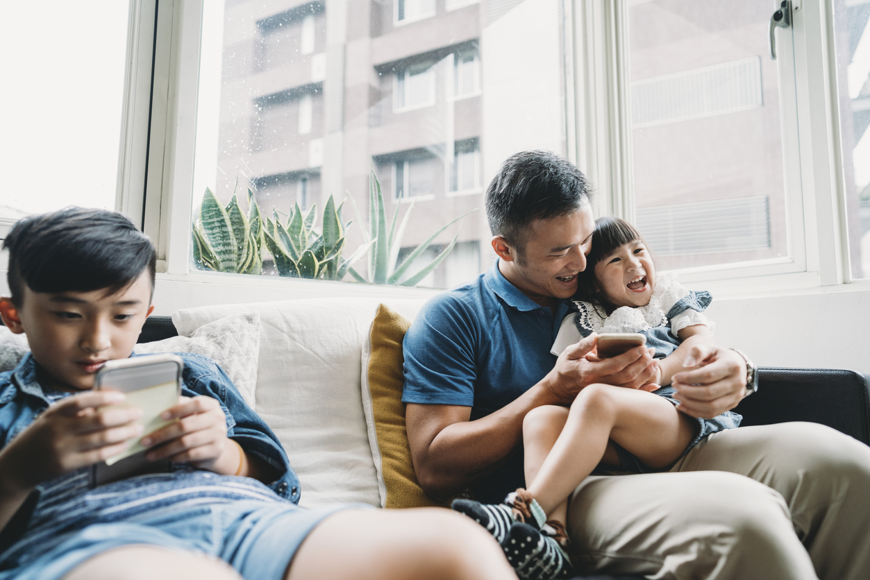 Family sitting on the couch, absorbed in their phones.