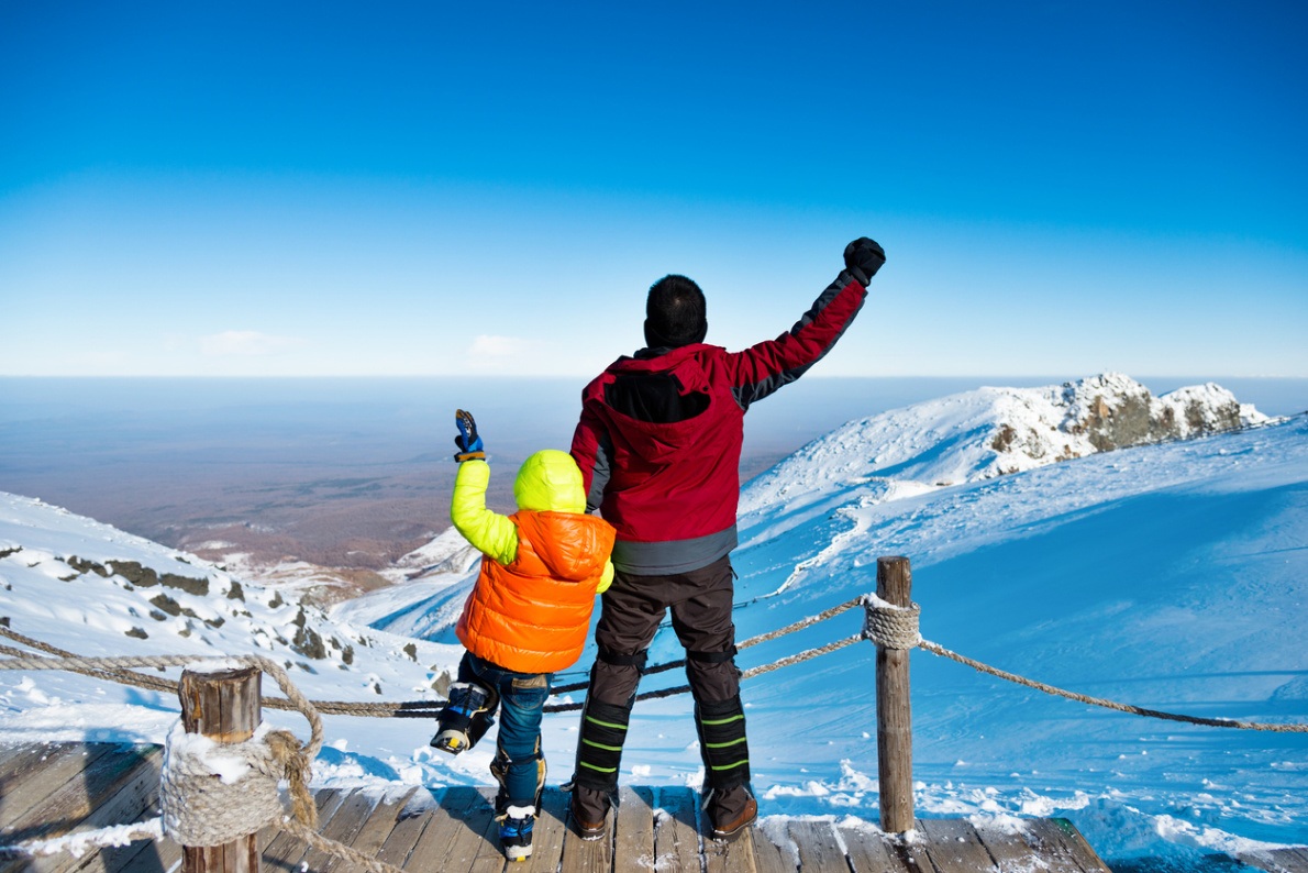 Father and son successfully climb a mountain.