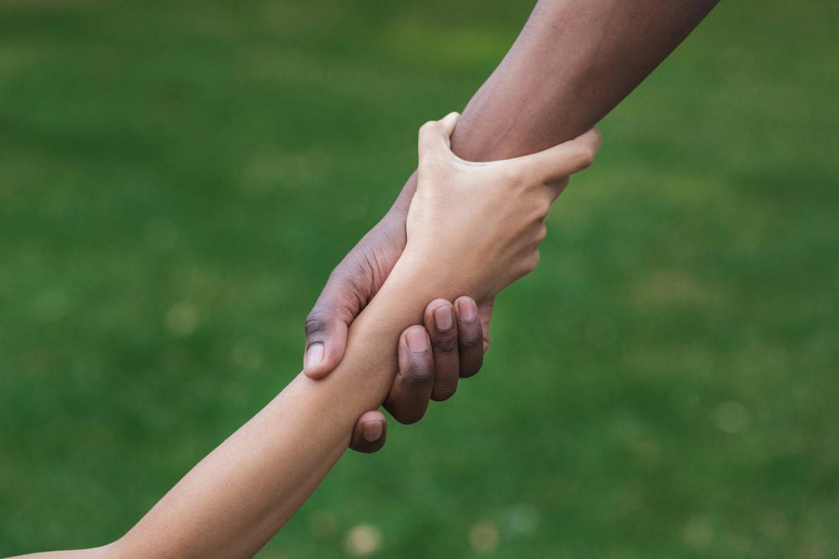 Multi ethnic friends clasping wrists in trusting.