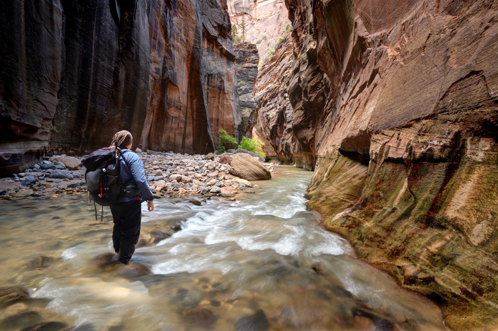 Woman hiking in the narrows of a canyon.