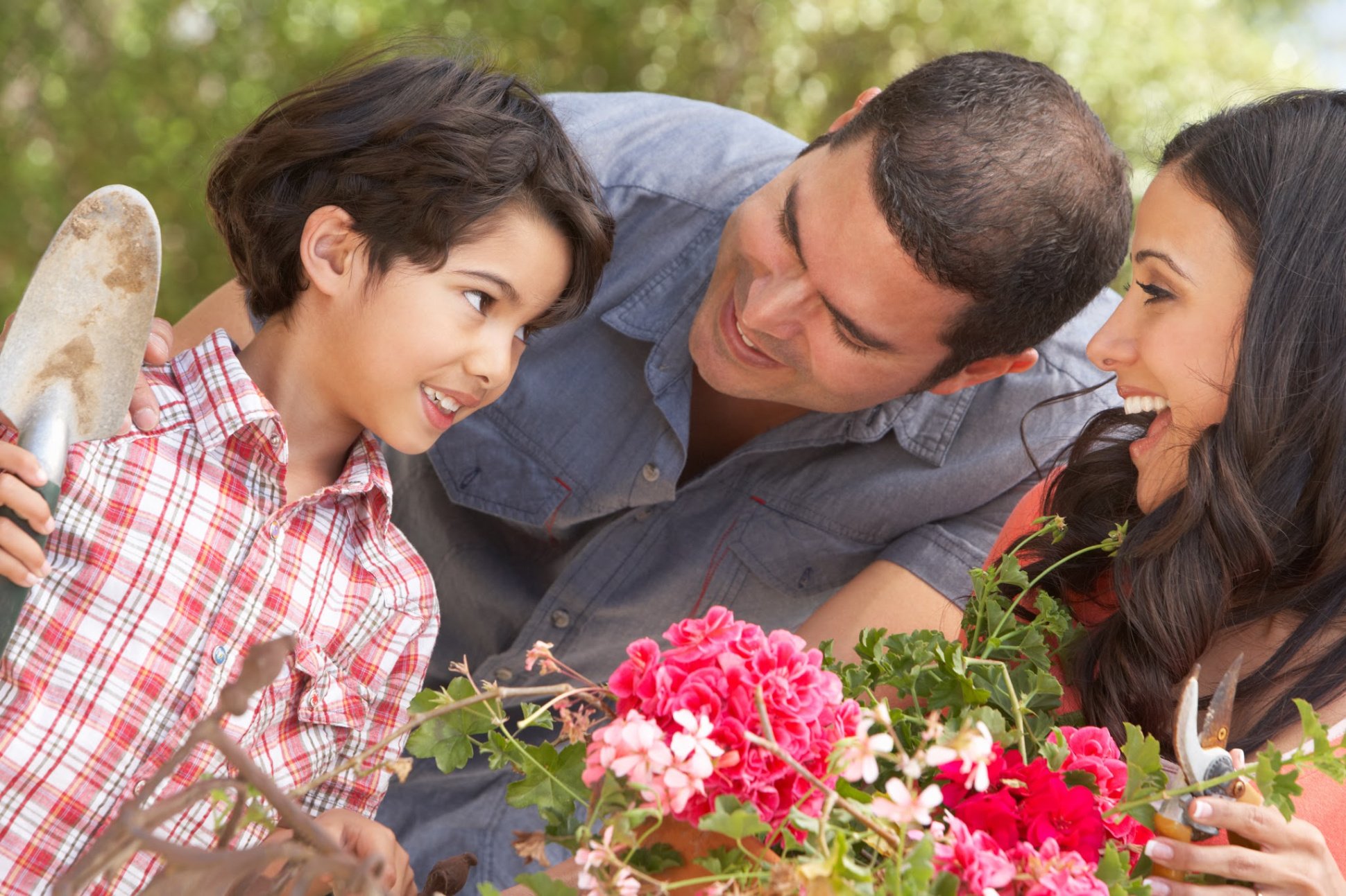 Hispanic Family Working In Garden Tidying Pots looking at eachother