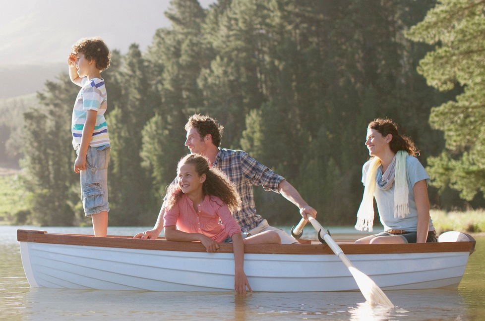 Father guiding family in a rowboat.