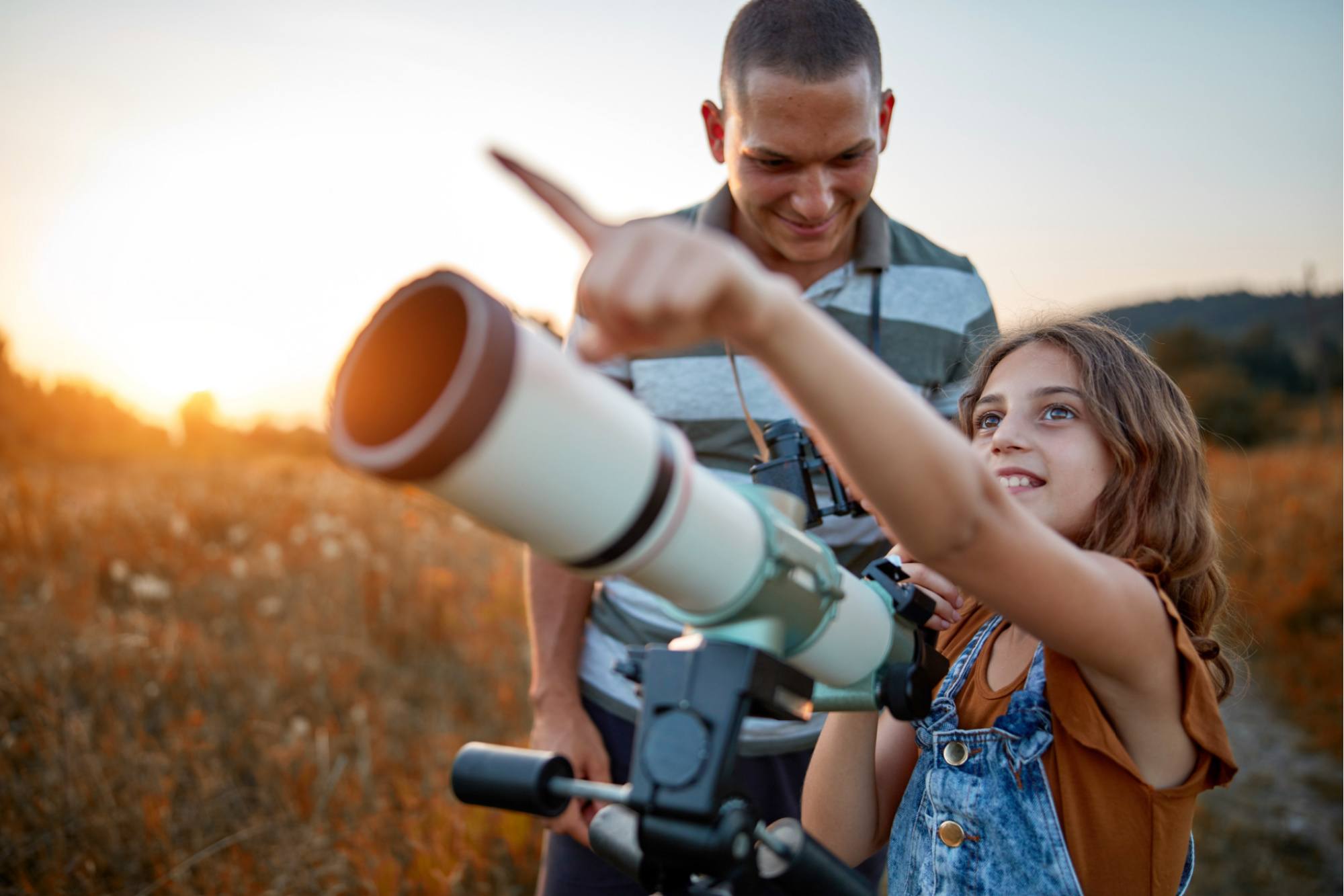 Father and daughter looking through a telescope.