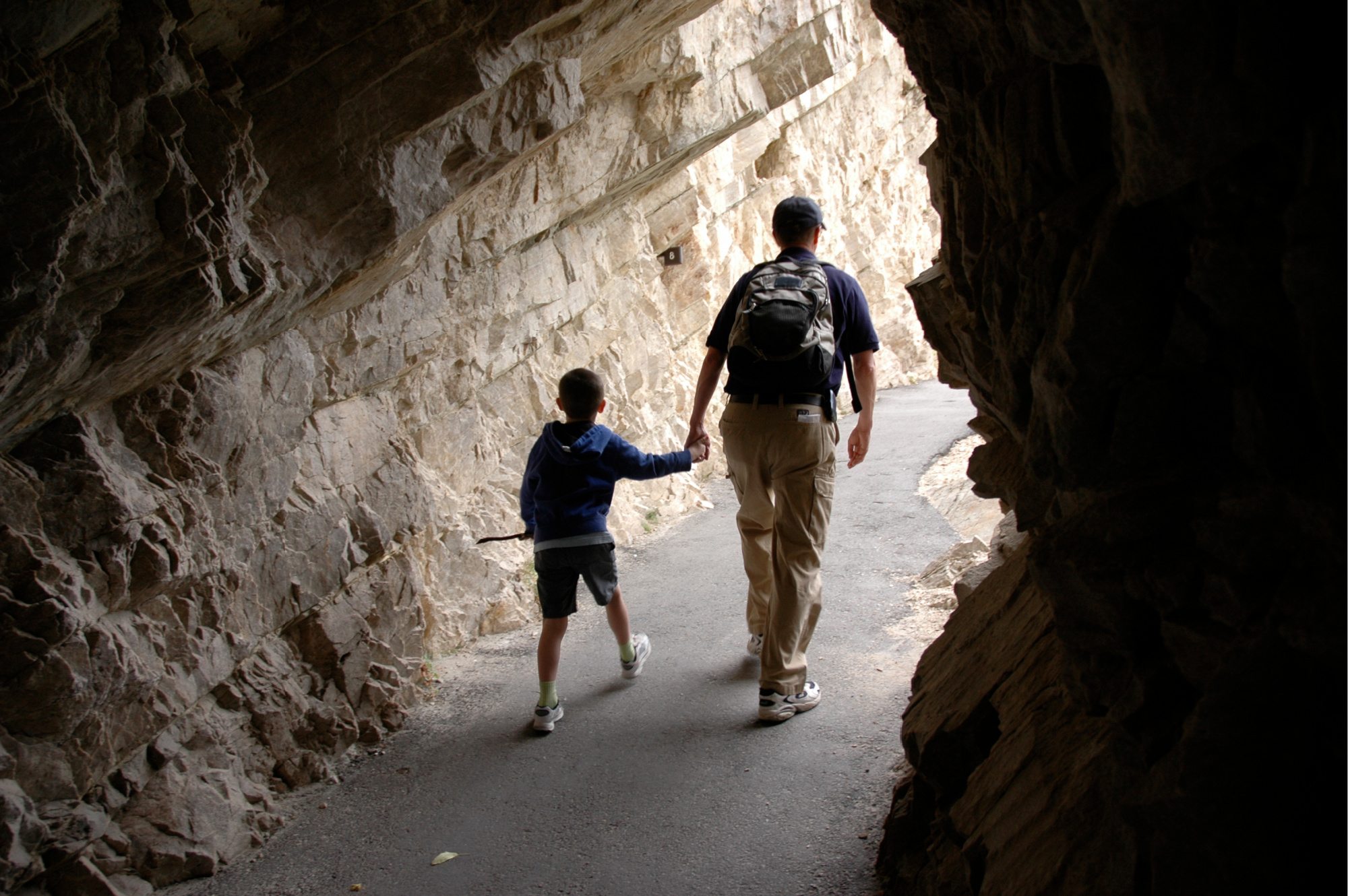 Father and son holding hands walking in a cave.