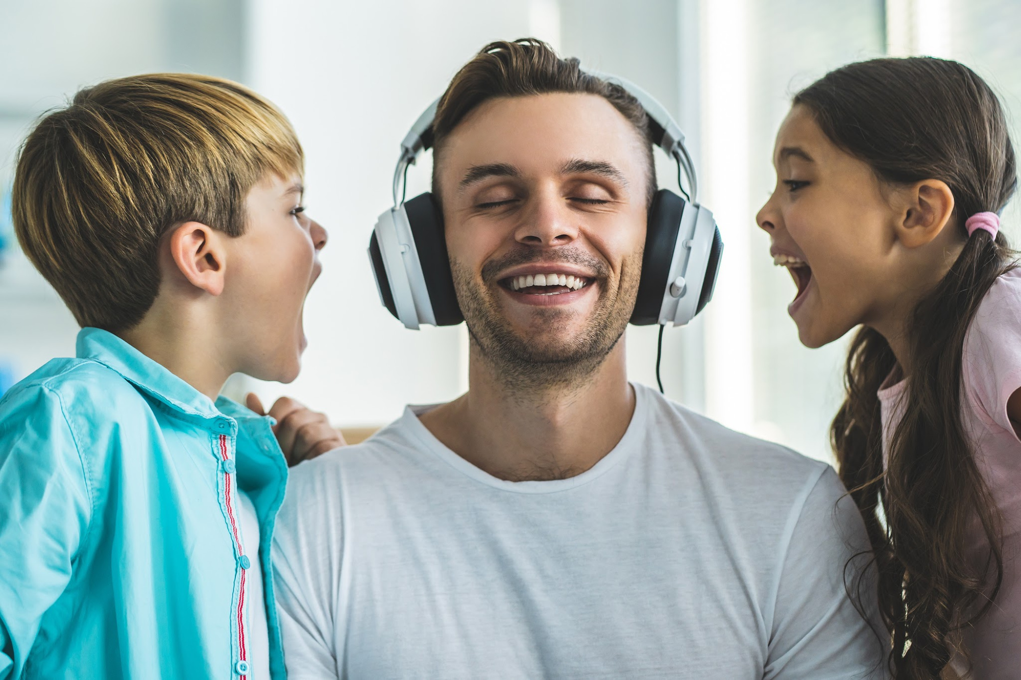 A father ignores his screaming children while listening music in headphone