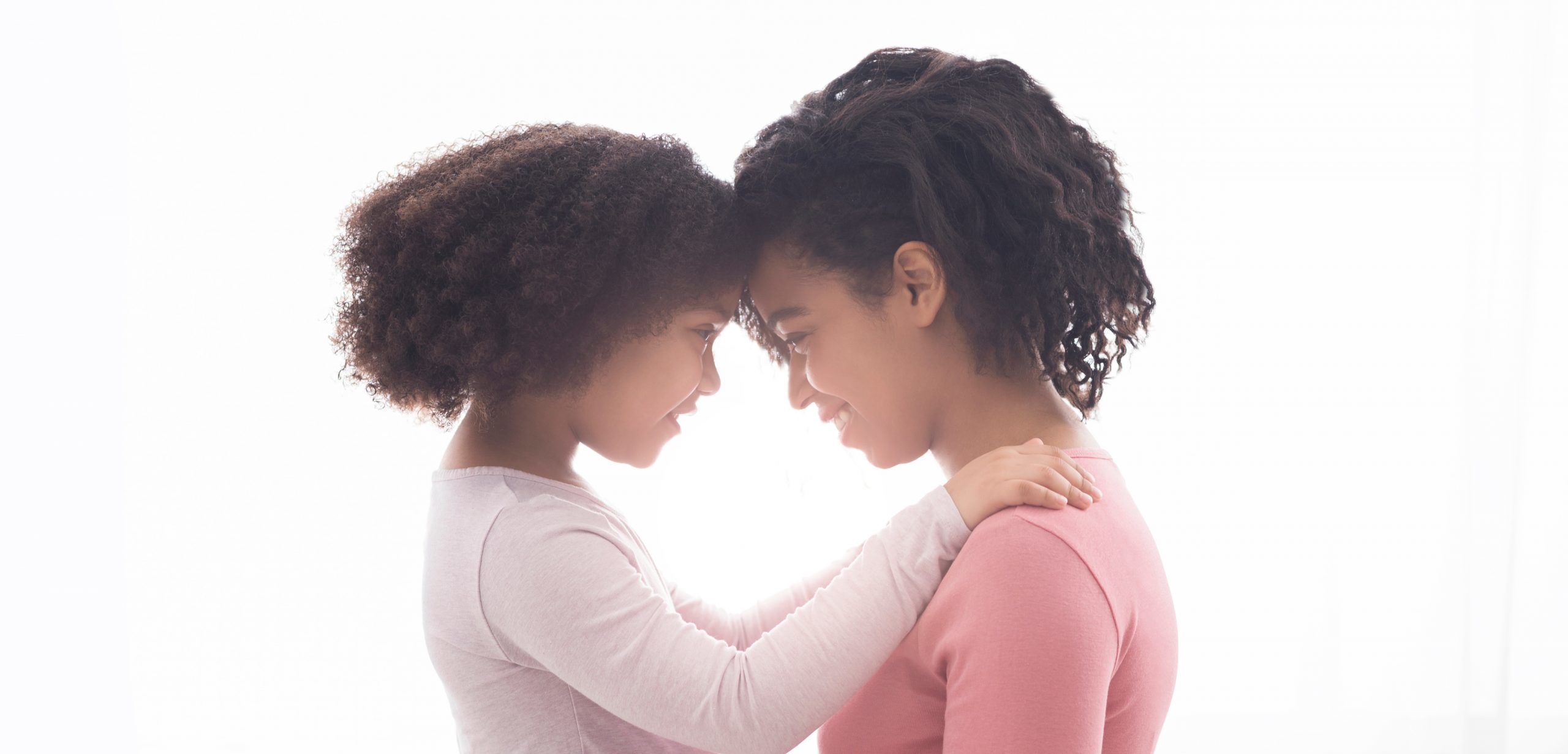 Mother and daughter touching heads, smiling.