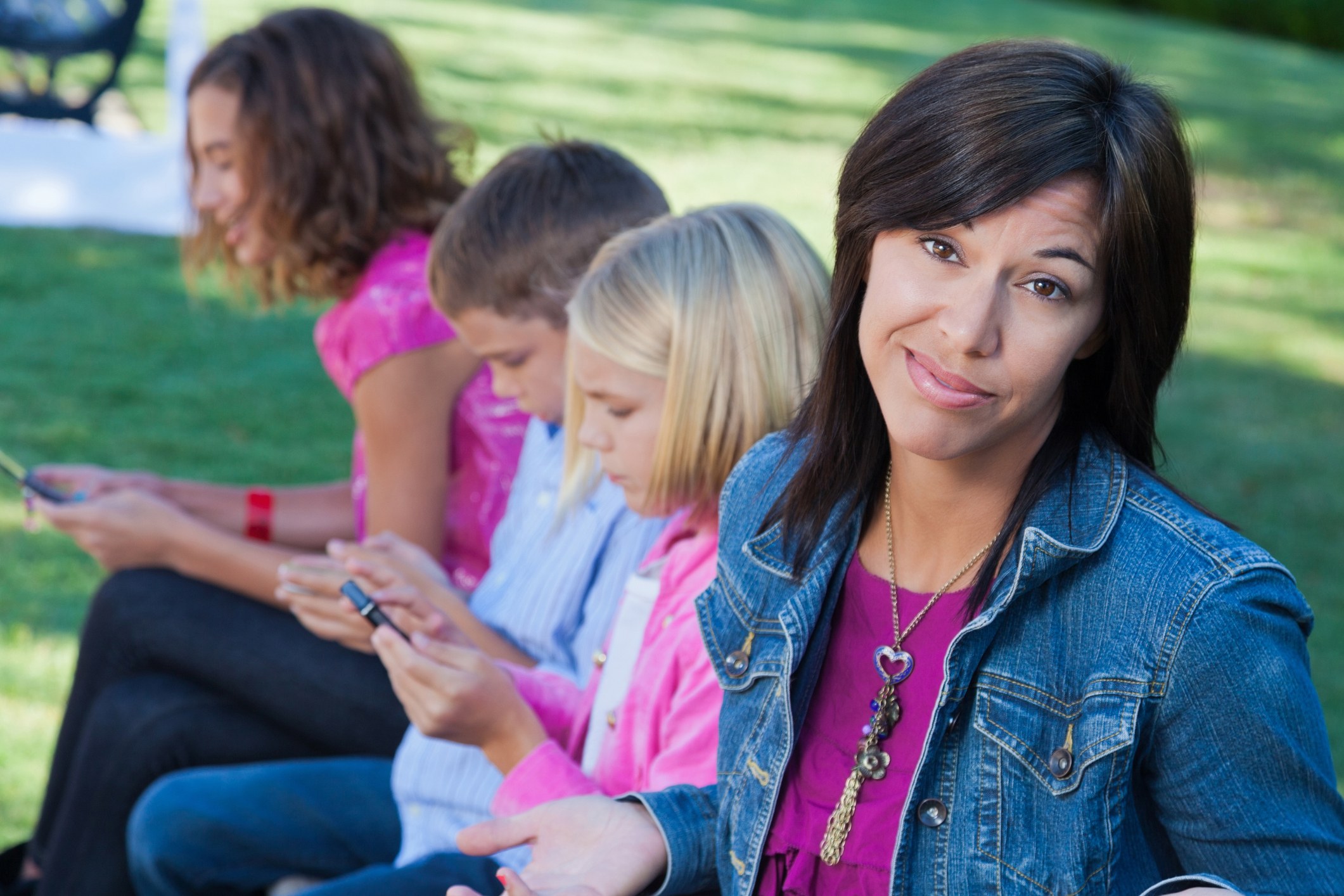 Frustrated mother makes a face while her children are in the background using smart phones.