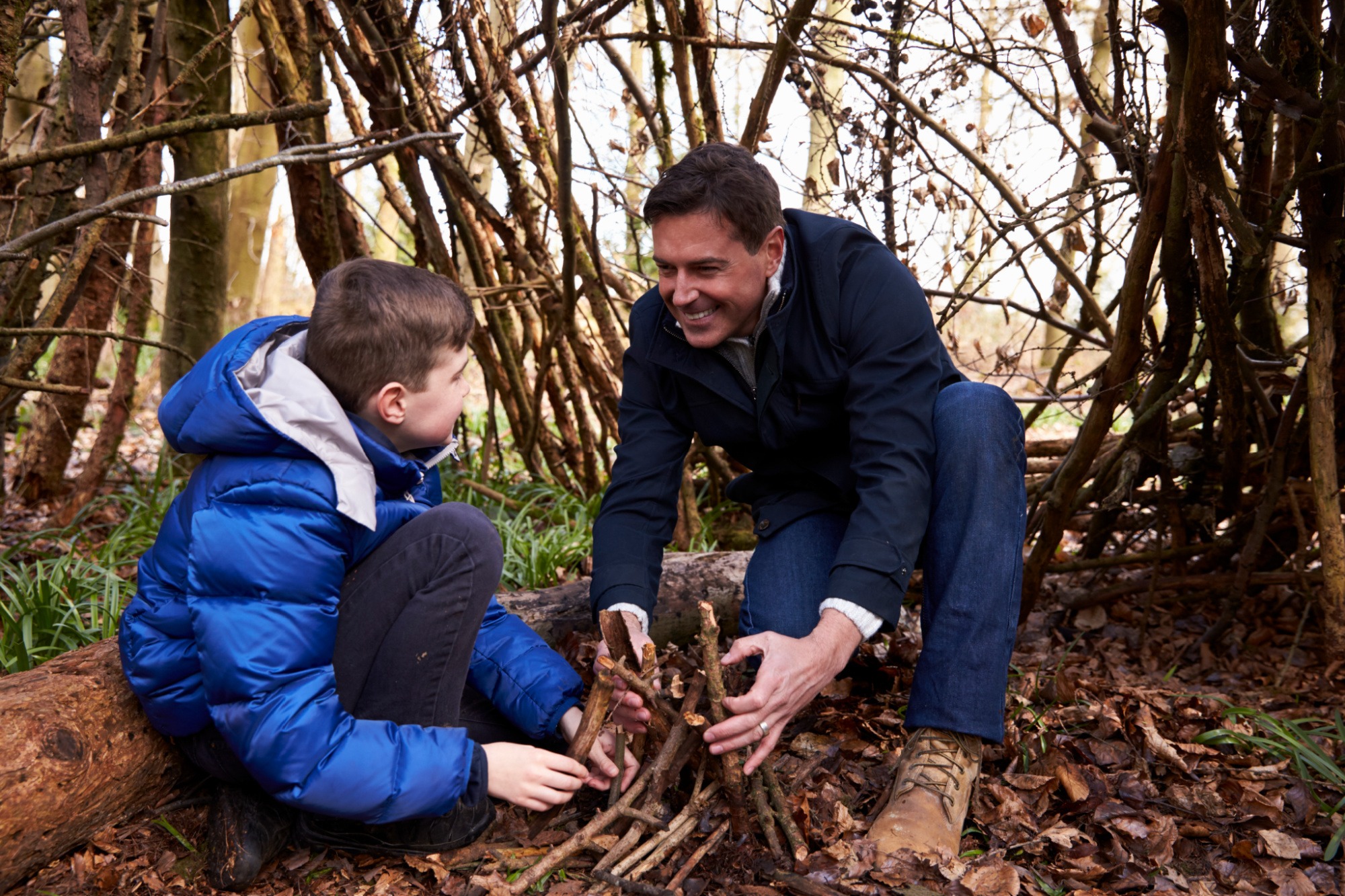 Father teaching his son how to build a campfire.