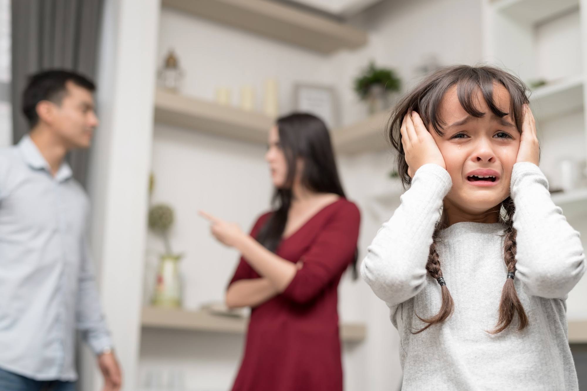 Domestic violence and Family conflict concept. Sadness little girl against blured of mother fighting father with quarrel at home.