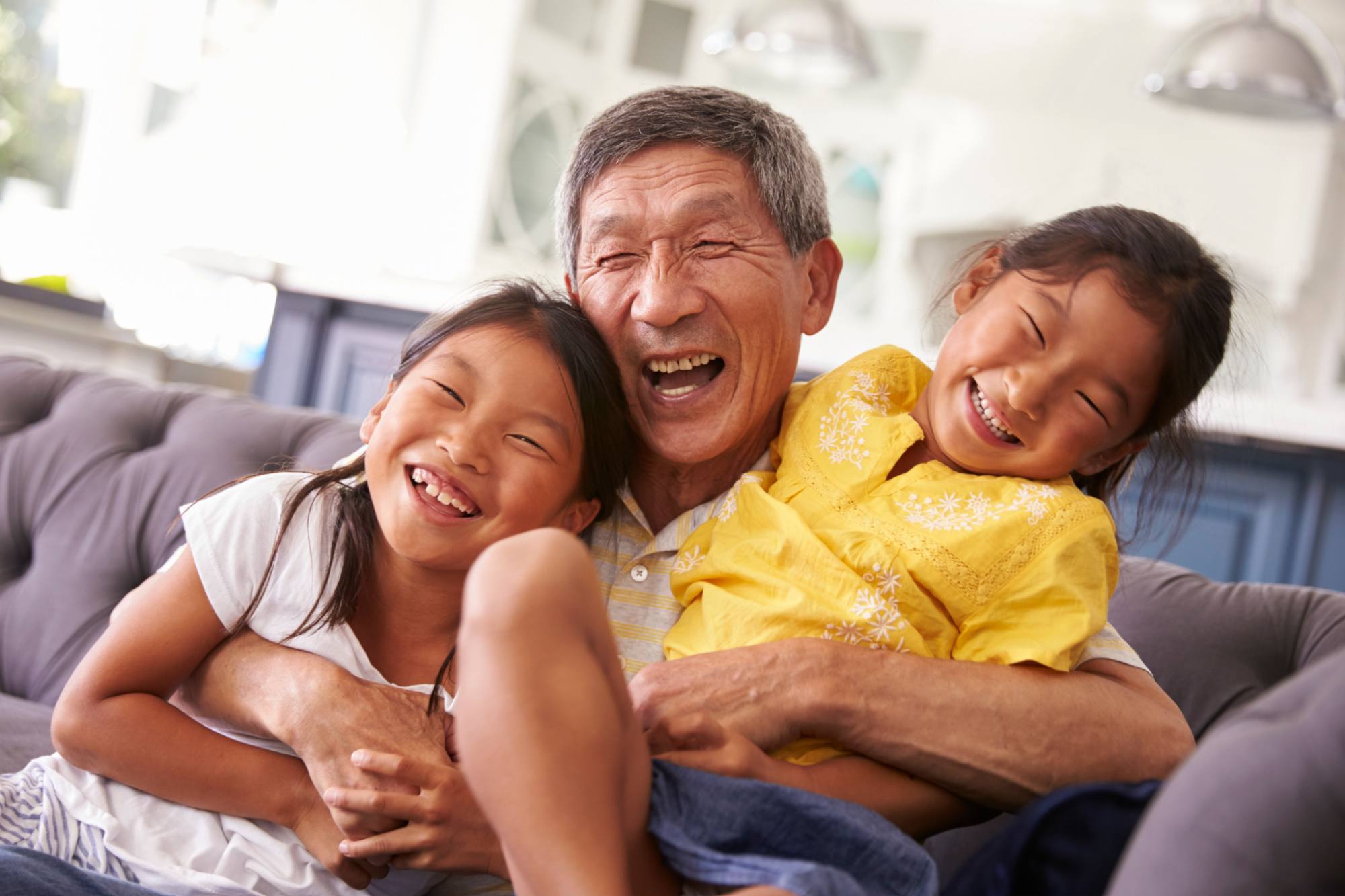 Oriental grandfather and his grandchildren laughing.