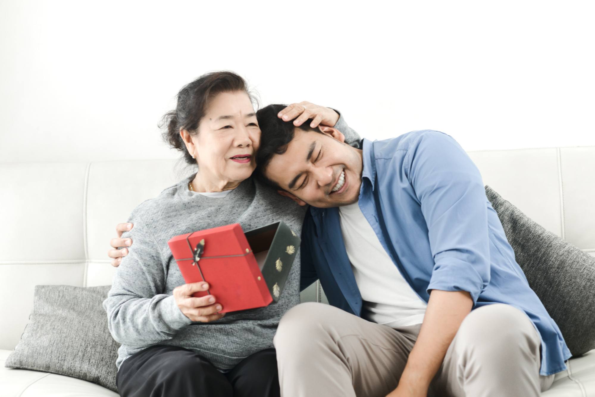 Happy Asian man giving gift box to his mother