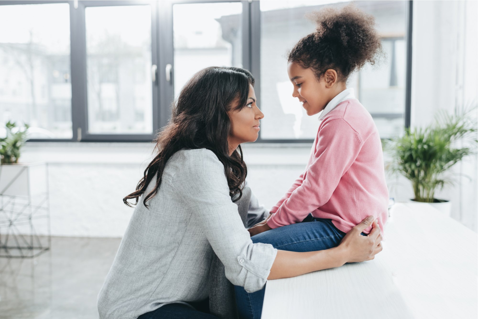 side view of african american mother talking with her daughter indoors