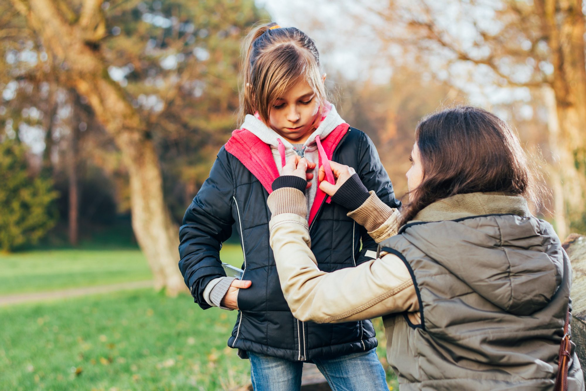 Mother helps a daughter with her coat.