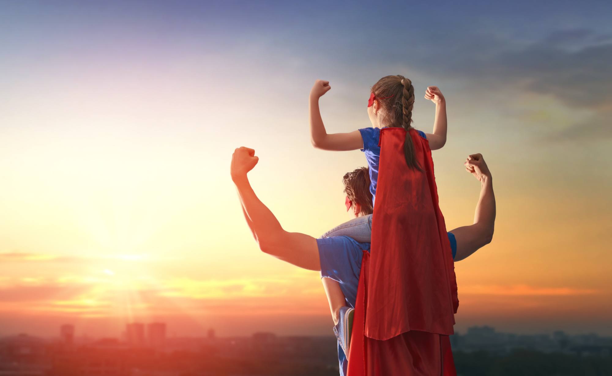 Happy loving family. Dad and his daughter playing outdoors. Daddy and child girl in an Superhero's costumes.