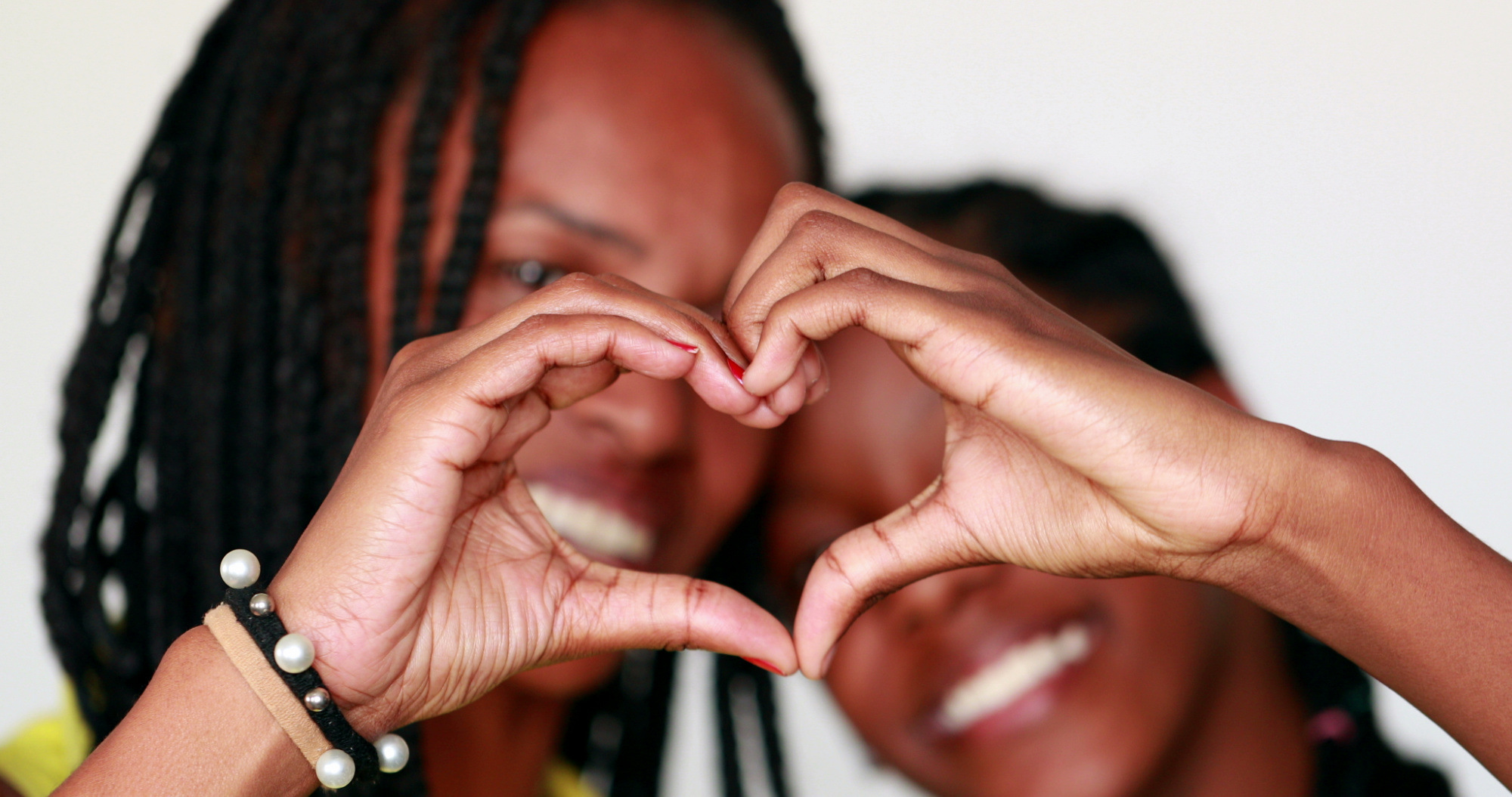 Mother and daughter making a heart with their hands.